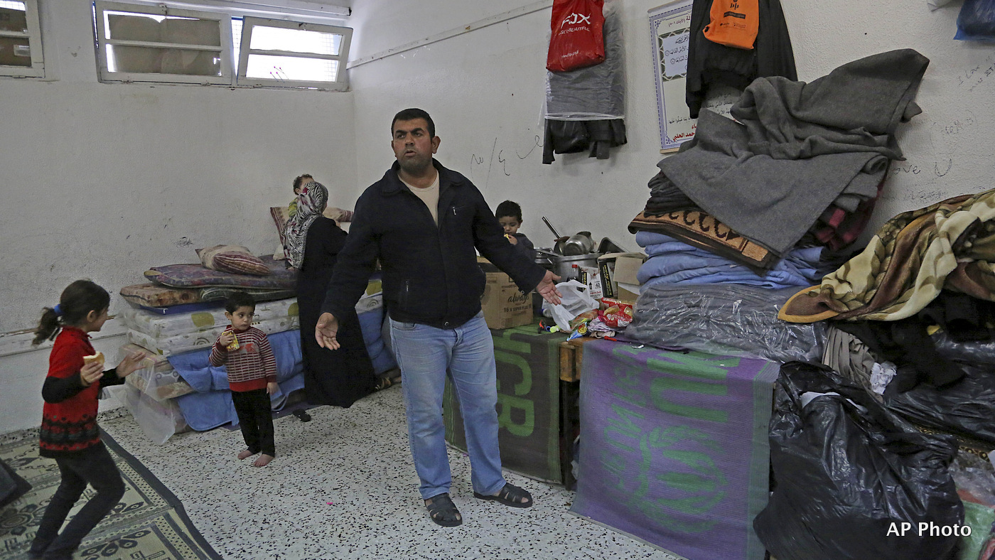 Sufian Wadiya, 36, stands in front of his family's belongings in a classroom at a U.N. school where he and his eleven family members live after their home was destroyed by Israeli strikes during last summer's Israel-Hamas war, in Gaza city, northern Gaza Strip, Tuesday, Jan. 27, 2015. The U.N. Relief and Works Agency said it suspended an aid program for Gaza residents displaced by the war because of a large shortfall in funds from donor countries. Robert Turner, head of the U.N. agency in Gaza, says that "virtually none" of the $5.4 billion pledged by the international community in aid to Gaza has reached Gaza and that this is "distressing and unacceptable." (AP Photo/Adel Hana)