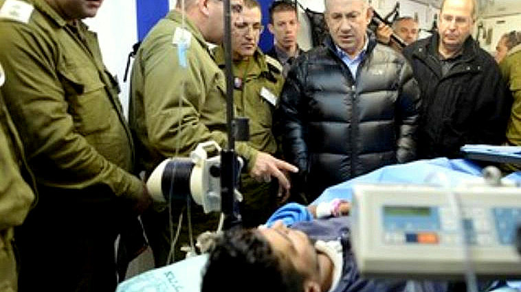 Netanyahu looks at a Syrian rebel fighter being treated in an IDF field hospital. (Photo: Kobi Gideon/GPO)
