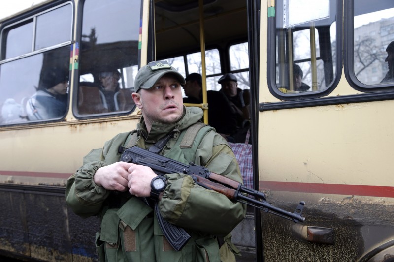 A Ukrainian soldier holds a weapon as people wait on a bus to leave the town of Debaltseve in Artemivsk, Ukraine, Tuesday, Feb. 3, 2015. Since the unrest in eastern Ukraine surged anew in early January, the separatists have made notable strides in clawing territory away from the government in Kiev. Their main offensive is now directed at Debaltseve a government-held railway junction once populated by 25,000 people that lies between the rebel-held cities of Luhansk and Donetsk. Almost 2,000 residents have fled in the last few days alone. (AP Photo/Petr David Josek)