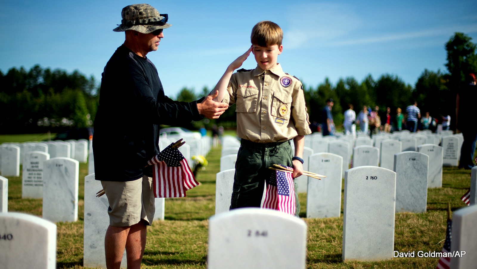 Retired U.S. Air Force Chief Master Sgt. Jackie Powell, left, of Canton, Ga., gives some instruction on saluting to Boy Scout Logan Schell, 12, of Cumming, Ga., as they place flags at the graves of military service members ahead of the Memorial Day holiday at Georgia National Cemetery, Saturday, May 25, 2013, in Canton, Ga.