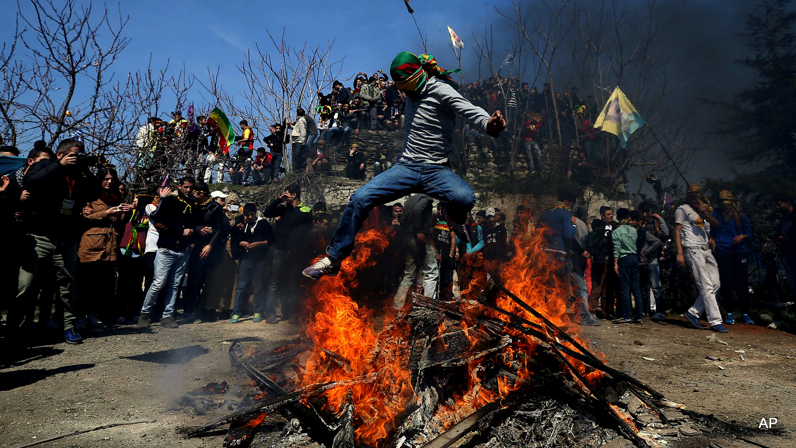 A masked supporter of imprisoned Kurdish rebel leader Abdullah Ocalan jumps over a Nowruz fire during the Nowruz celebrations in Istanbul, Turkey.