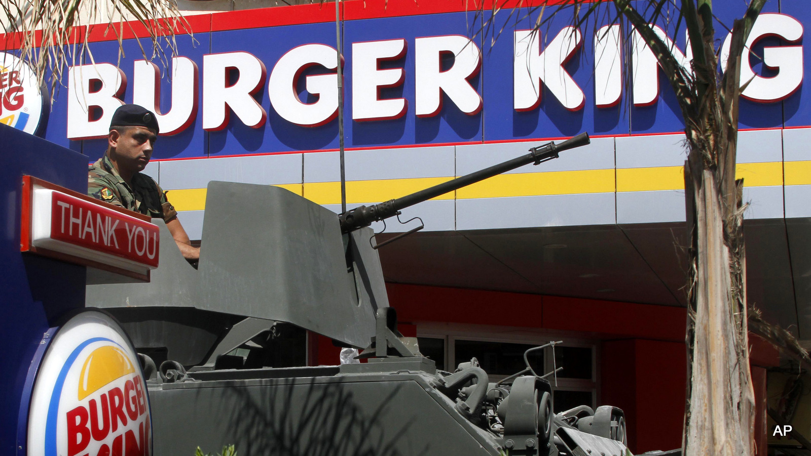 A Lebanese army soldier sits on his armored personnel carrier, as he stands guard outside the Burger King as part of stepped up security measures, in the southern port city of Sidon, Lebanon, Sept. 15, 2012. (AP/Mohammed Zaatari)