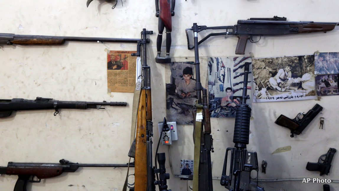 This Wednesday, Feb. 25, 2015 photo shows, photos of gunsmith Bahktiyar Sadr-Aldeen as a child, center, and his father, right, hung on a wall at his gun shop, in Irbil, northern Iraq. Sadr-Aldeen, an Iraqi Kurd, has seen his business shoot up by 50 percent since last June, when the Islamic State took over the Iraqi city of Mosul.