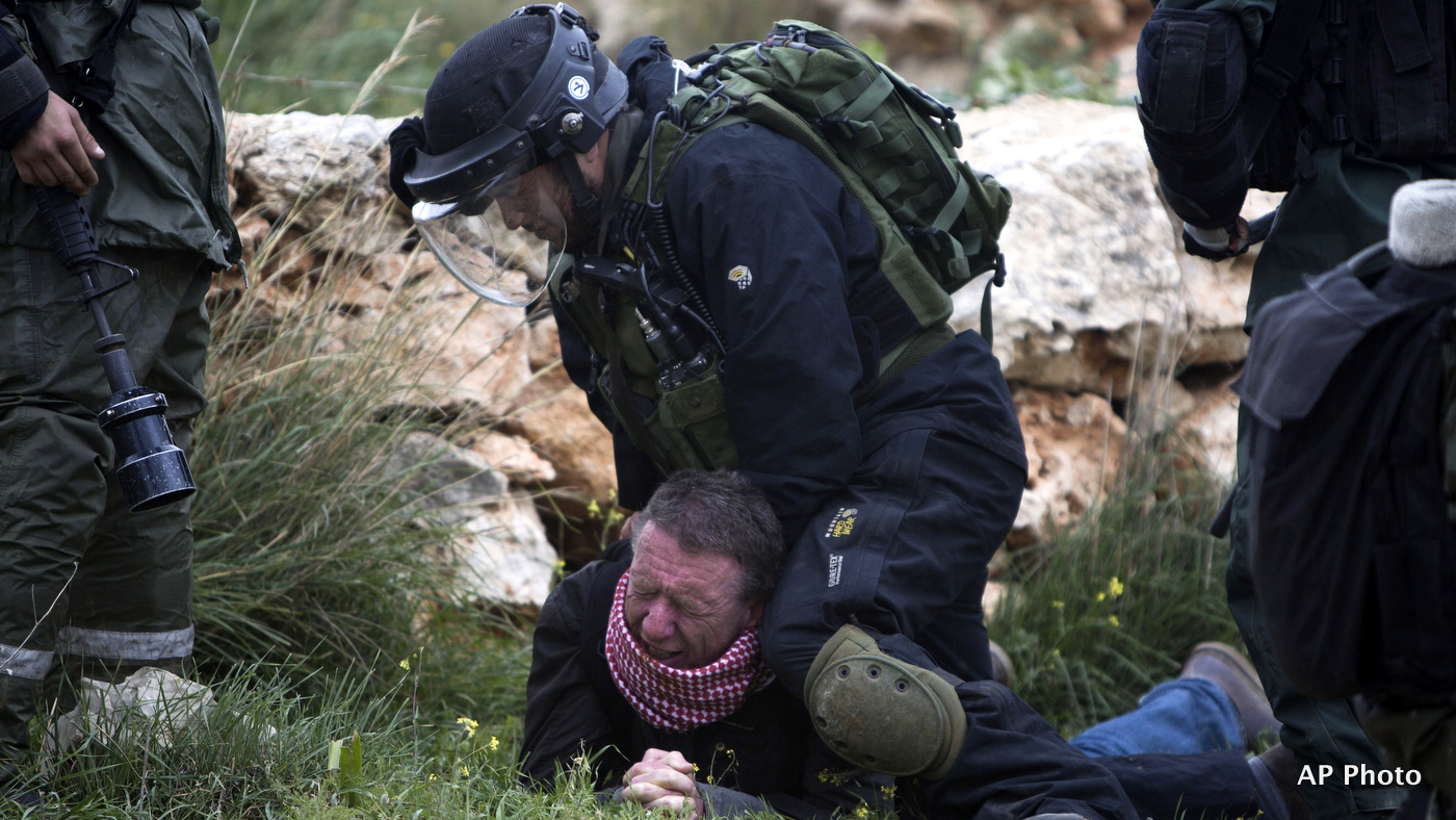 An Israeli border policeman detains a protester during a weekly demonstration against Israel's apartheid wall in the West Bank village of Bilin near Ramallah, Friday, Feb. 13, 2015.