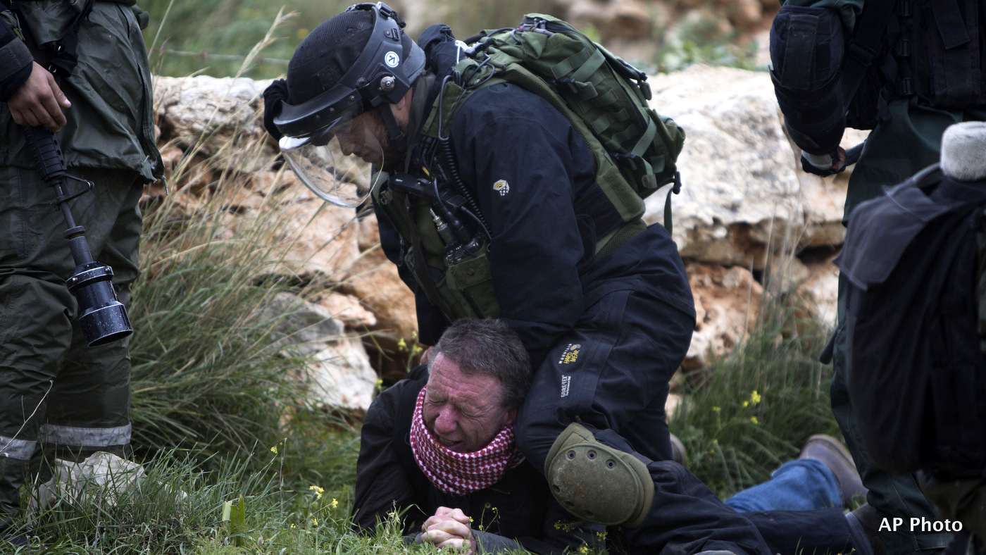 An Israeli border policeman detains a protester during a weekly demonstration against Israel's apartheid wall in the West Bank village of Bilin near Ramallah, Friday, Feb. 13, 2015. 