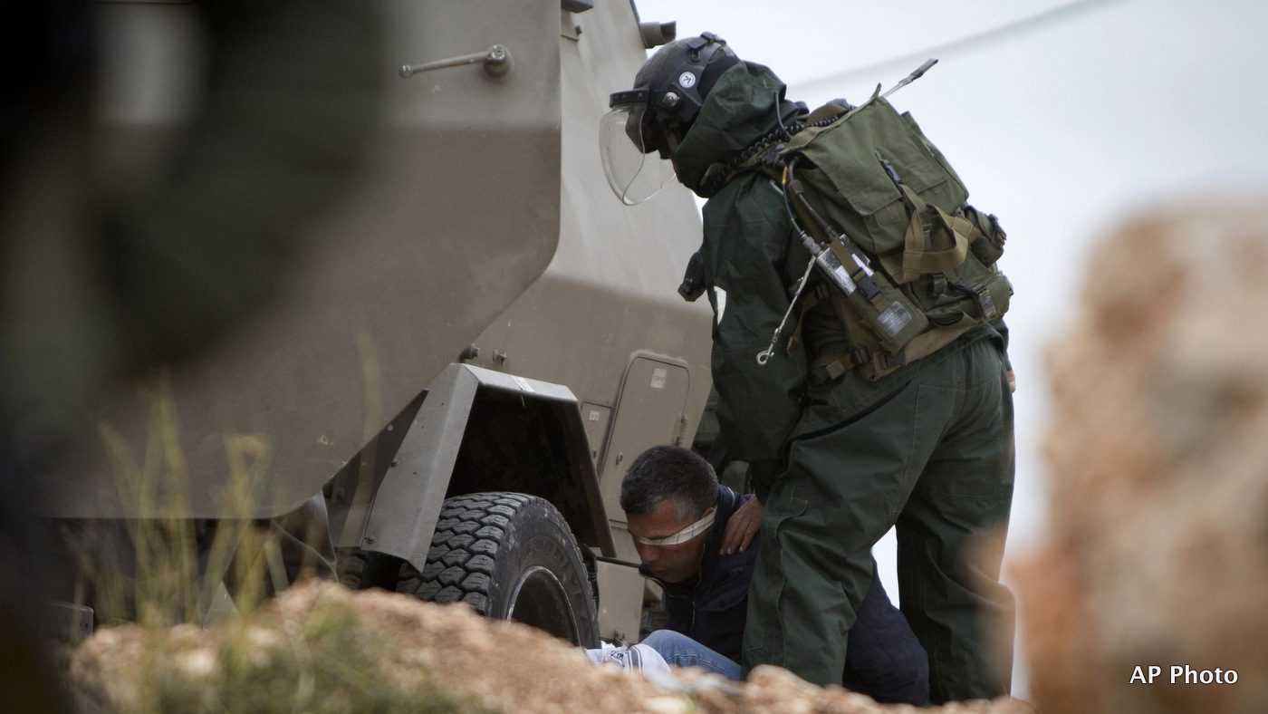 An Israeli border policeman detains a Palestinian protester during a weekly demonstration against Israel's separation barrier in the West Bank village of Bilin near Ramallah, Friday, Feb. 13, 2015. 