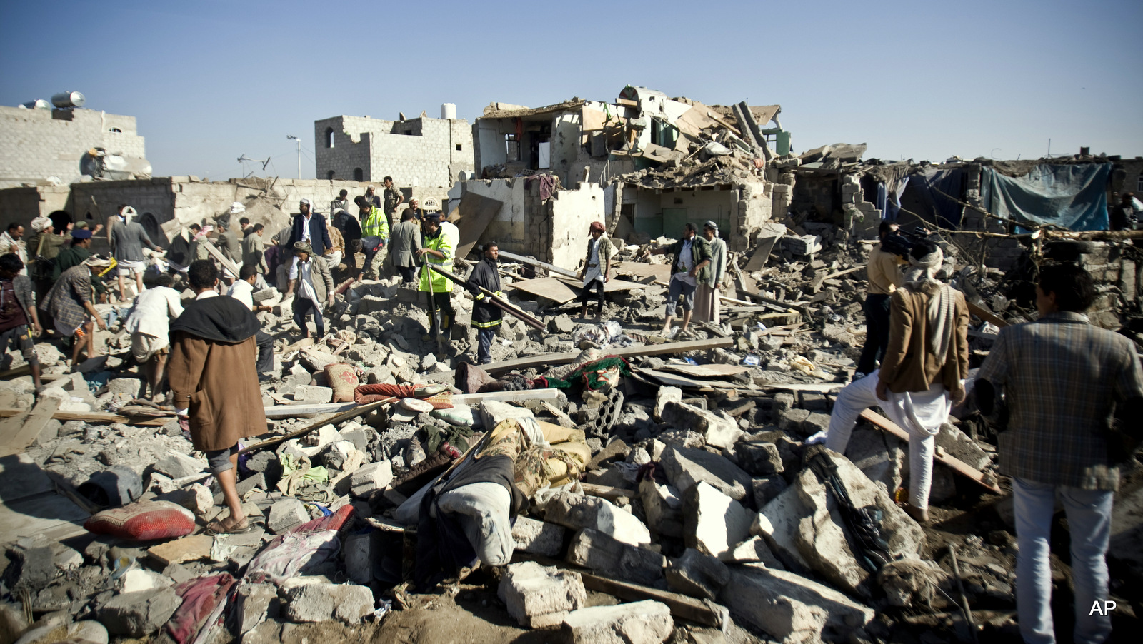 People search for survivors under the rubble of houses destroyed by Saudi airstrikes near Sanaa Airport, Yemen, Thursday, March 26, 2015. Saudi Arabia launched airstrikes Thursday targeting military installations in Yemen held by Shiite rebels who were taking over a key port city in the country's south and had driven the embattled president to flee by sea, security officials said.