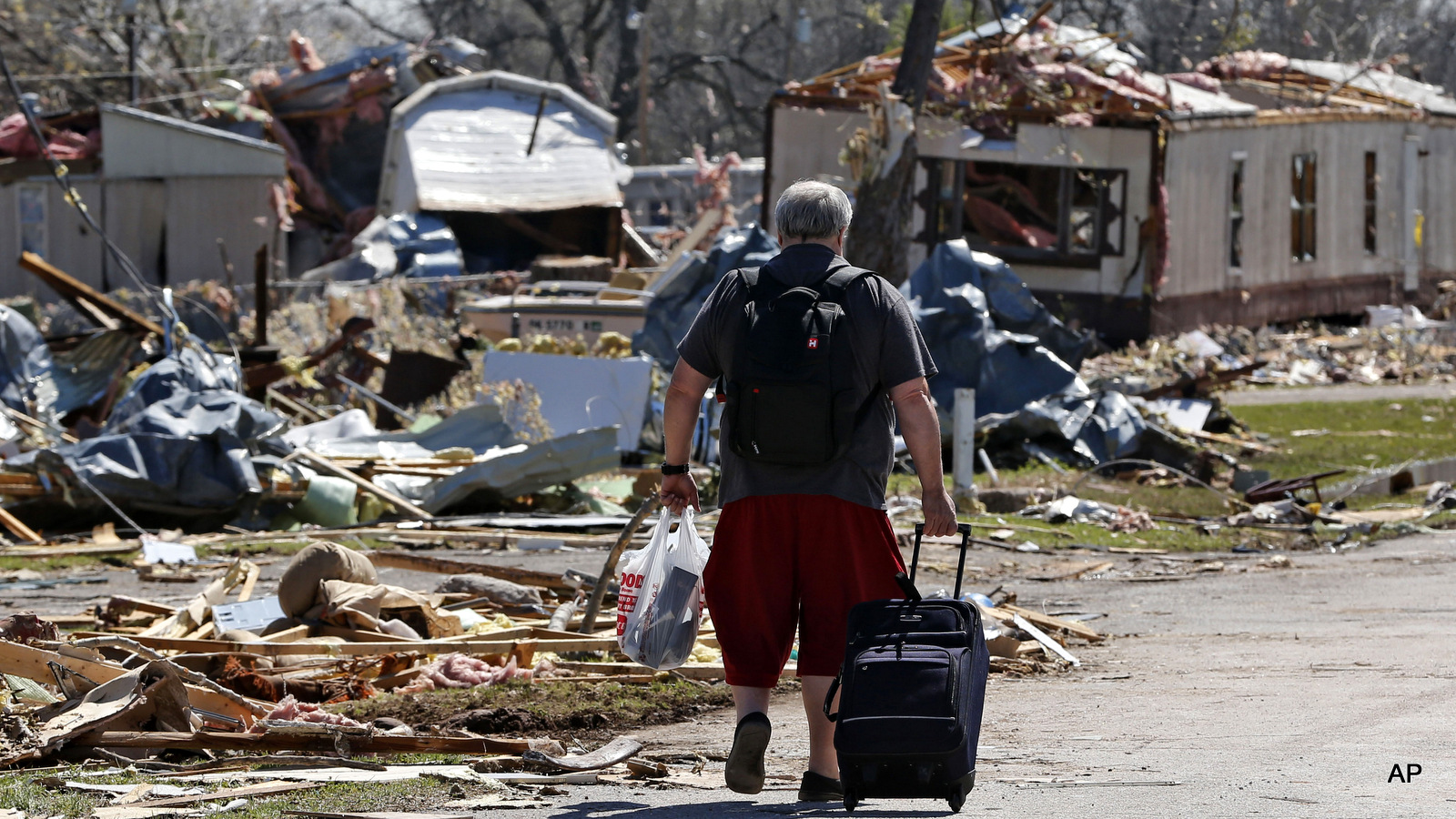 Robert Swanson carts out some of his belongings through a tornado-damaged mobile home park in Sand Springs, Okla., Thursday, March 26, 2015. (AP Photo/Sue Ogrocki)