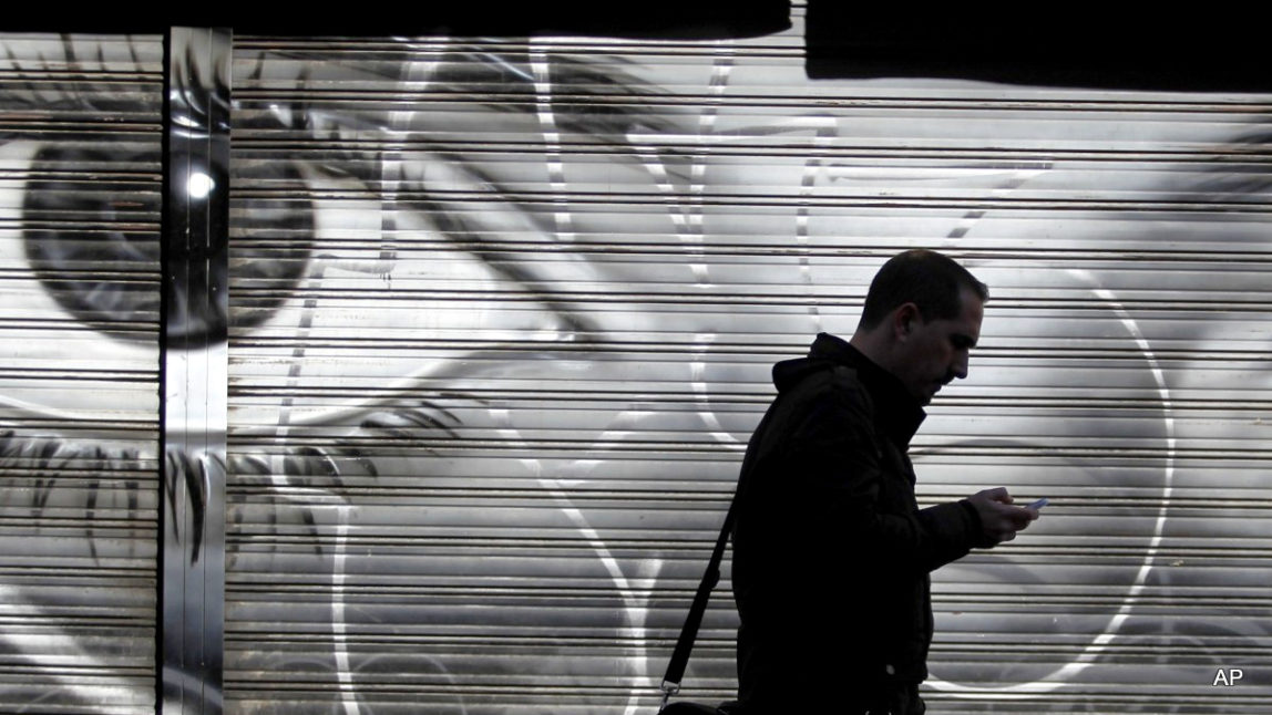 A man looks at his cell phone as he walks on the street.