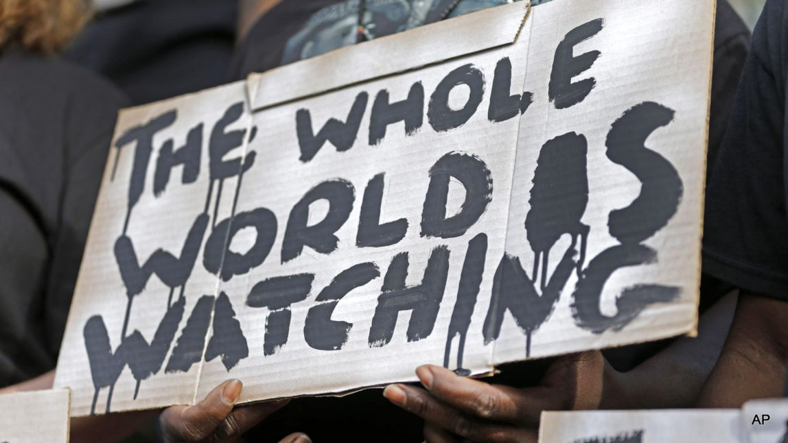 A man holds a sign during a protest for the shooting death of Walter Scott at city hall in North Charleston, S.C., Wednesday, April 8, 2015. Scott was killed by a North Charleston police officer after a traffic stop on Saturday. The officer, Michael Thomas Slager, has been charged with murder.