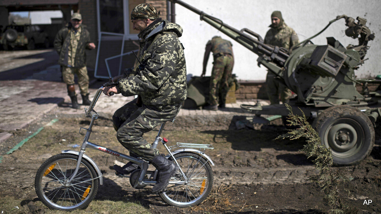 A Ukrainian serviceman rides a bicycle in Shyrokyne, eastern Ukraine, Wednesday, April 15, 2015. Russia and Ukraine agreed in Berlin on Monday to call for the pullback of smaller-caliber weapons from the front lines of the conflict that has claimed more than 6,000 lives.