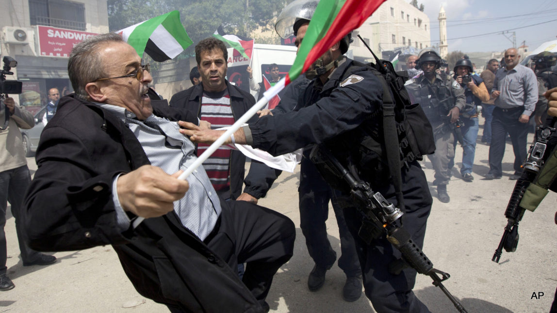 Palestinians protester is pushed by Israeli border policemen during a protest marking the Land Day in the West Bank village of Hawara near Nablus, Monday, March 30, 2015.