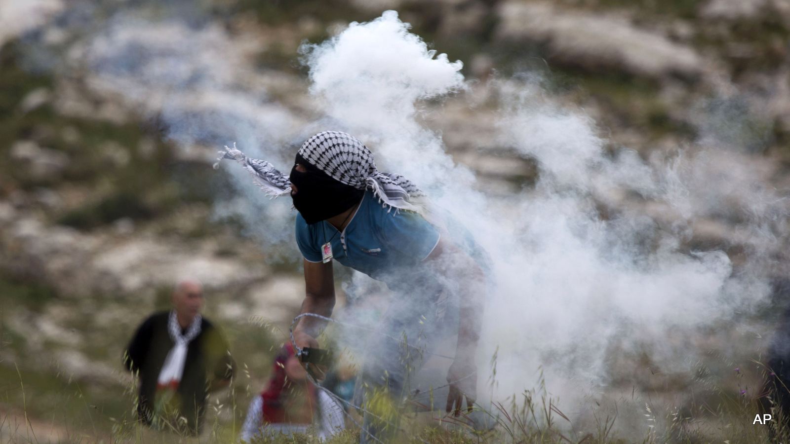 A Palestinian throws back a tear gas canister toward Israeli troops during a protest marking Land Day, in the West Bank village of Nabi Saleh near Ramallah.