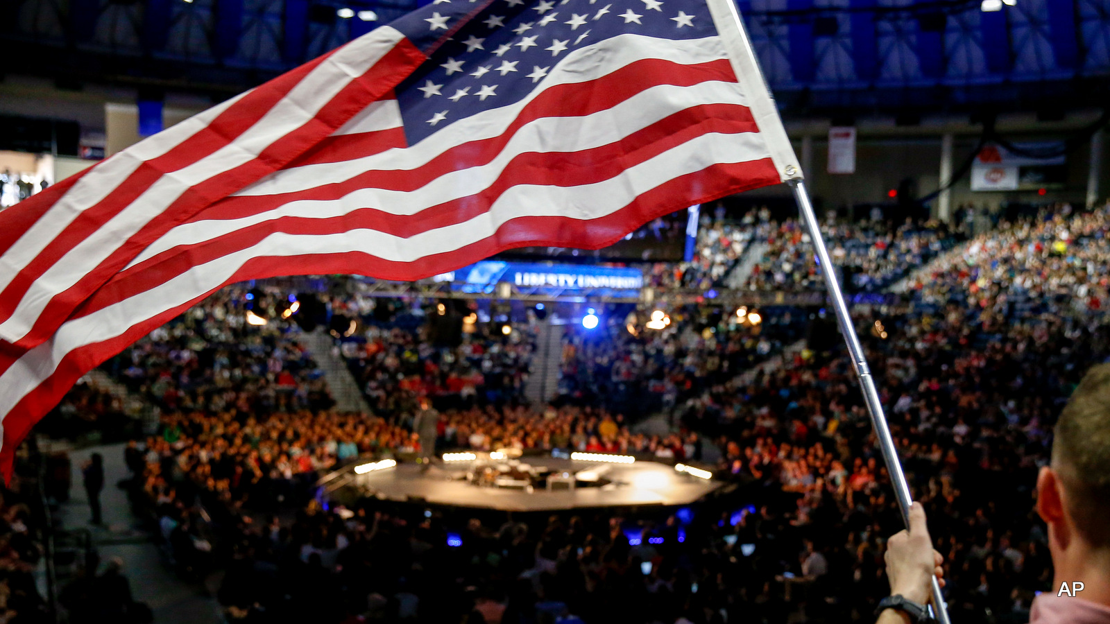 A man in the audience waves an American flag after Ted Cruz announced his campaign for president at Liberty University founded by the late ultra-conservative preacher Jerry Falwell, in Lynchburg, Va.