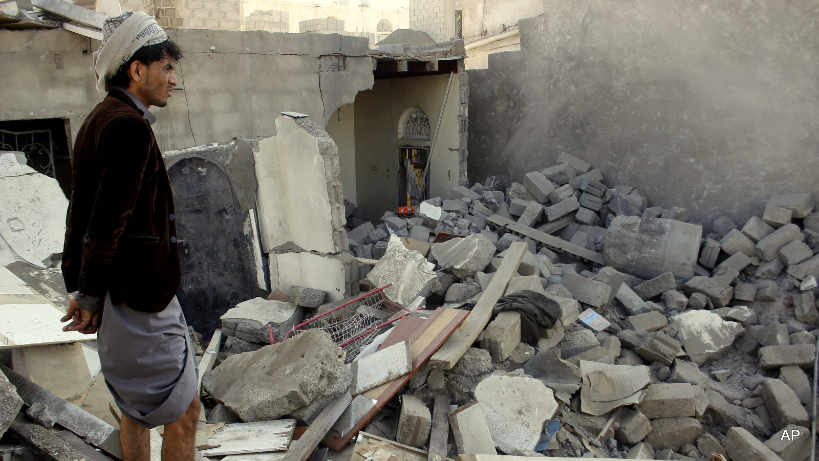 A Yemeni man stands at his house destroyed by Saudi airstrikes near Sanaa Airport, Yemen, Tuesday, March 31, 2015. (AP Photo/Hani Mohammed)