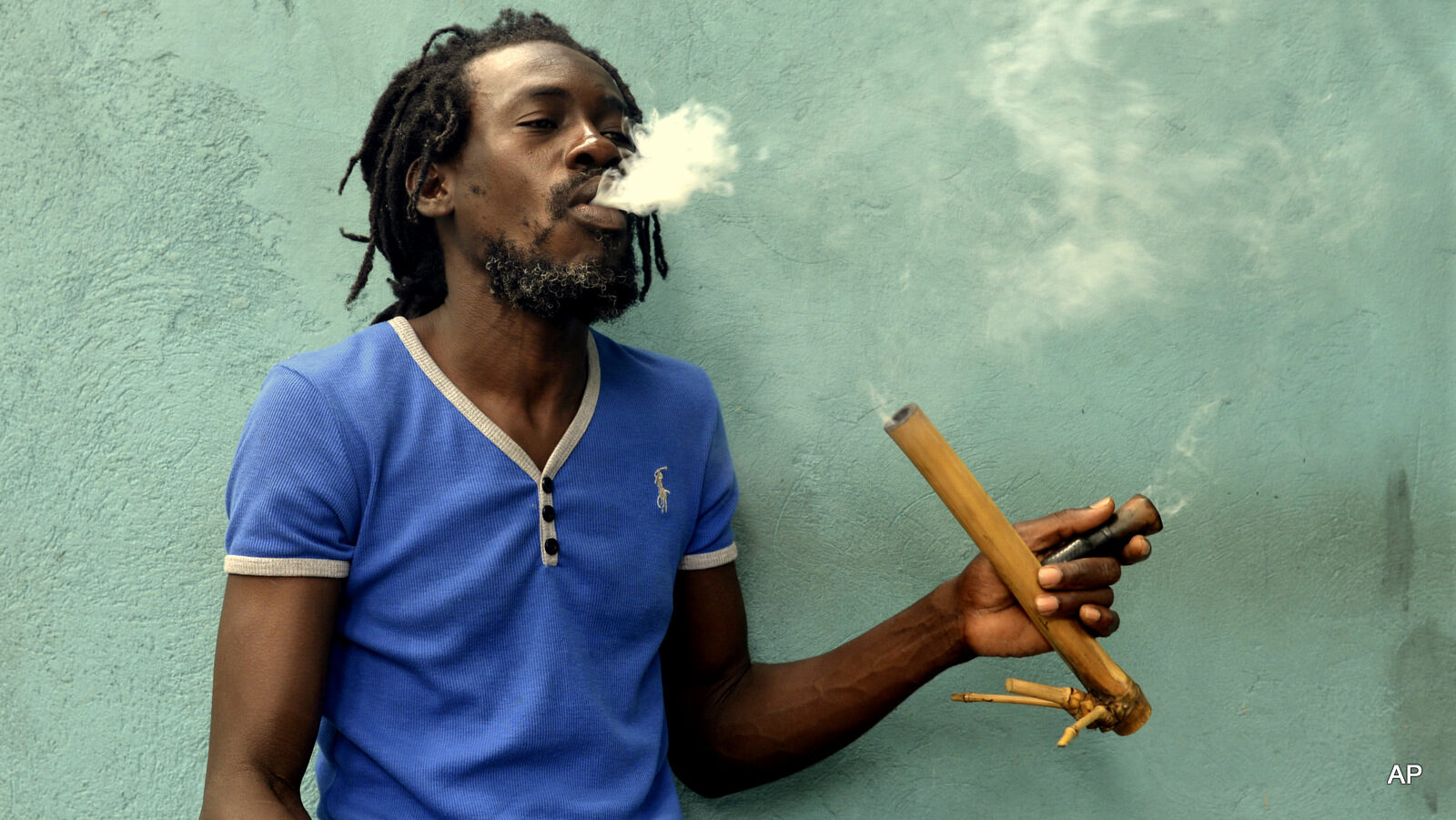 A Jamaican Rastafarian known as Nature smokes marijuana outside the Trench Town Culture Yard Museum in downtown Kingston, Jamaica, Wednesday, April 15, 2015, where he works as a tour guide. Nature, like most adherents of the Rastafarian movement, said he smokes for spiritual purposes. Drug law amendments decriminalizing small amounts of pot and paving the way for a lawful medical marijuana sector came into effect Wednesday in Jamaica.