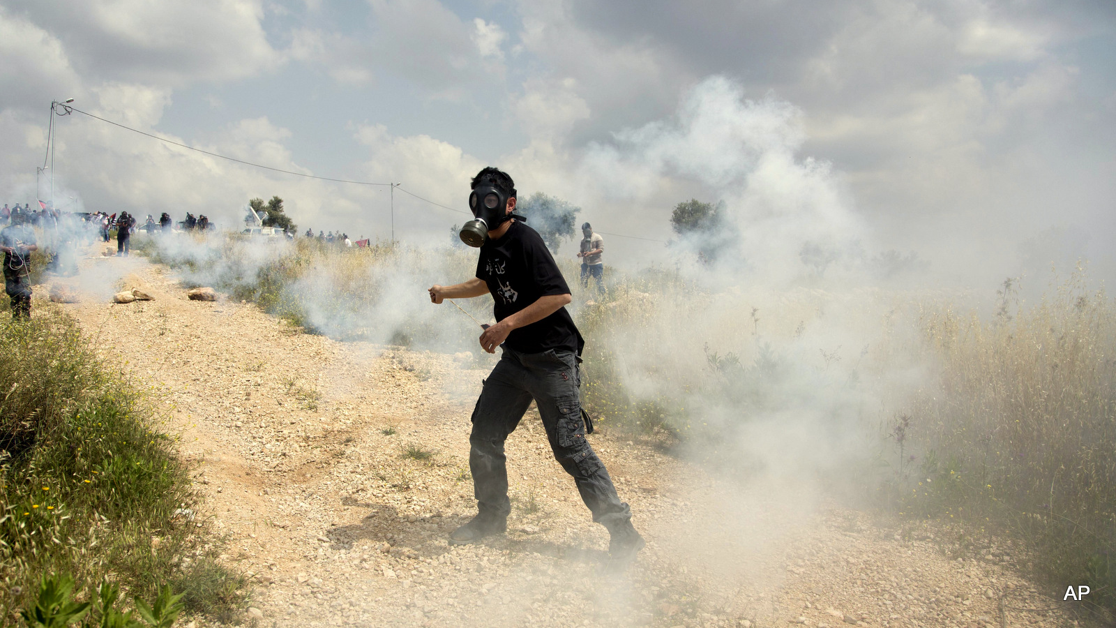 A Palestinian demonstrator uses a sling to throw back a tear gas canister fired by Israeli soldiers during clashes following a protest marking Palestinian "Prisoners' Day" in the West Bank village of Bilin, near Ramallah, Friday, April 17, 2015.