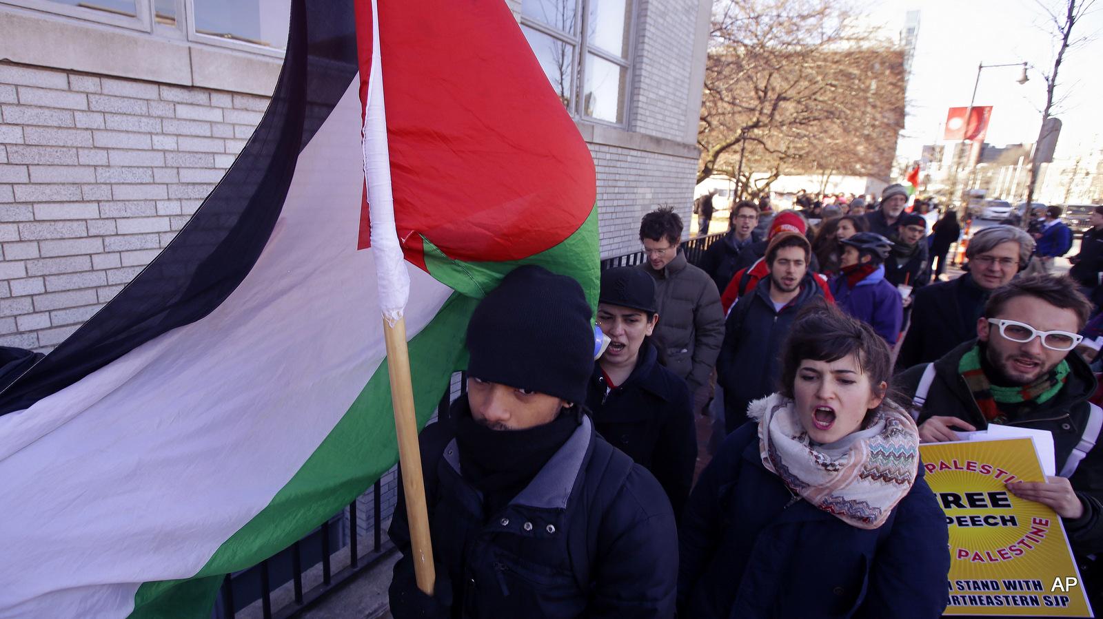A Northeastern University student choosing not to give his name carries a Palestinian flag during a protest in support of Palestine after a Northeastern University student organization, Students for Justice in Palestine