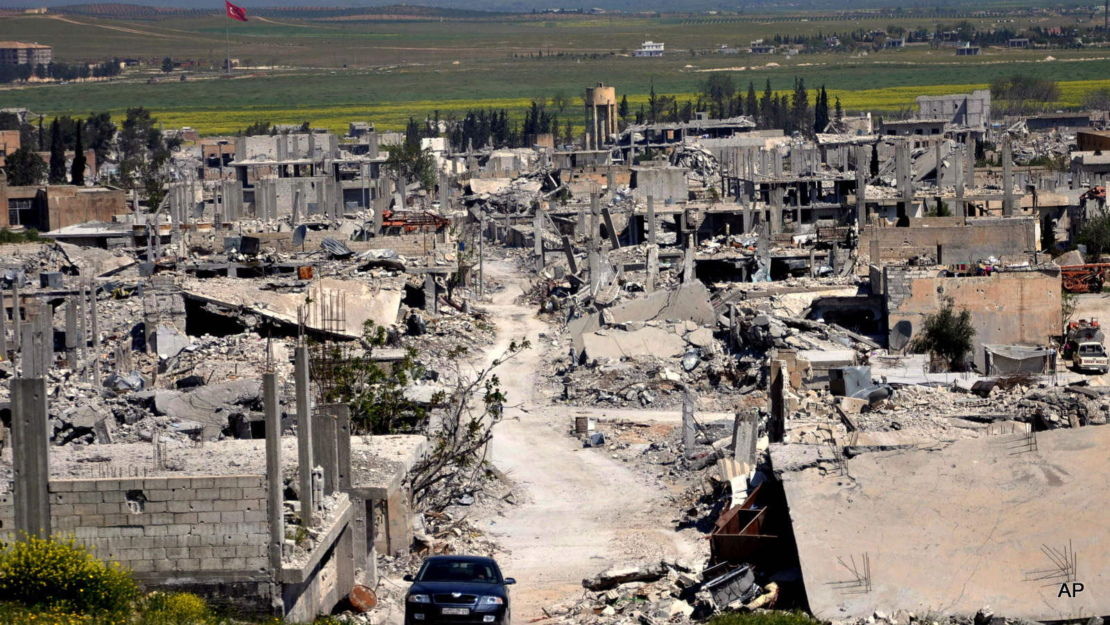 In this picture taken on Saturday, April 18, 2015, a car passes in an area that was destroyed during the U.S. bombing campaign in Kobani, north Syria. (AP Photo/Mehmet Shakir)