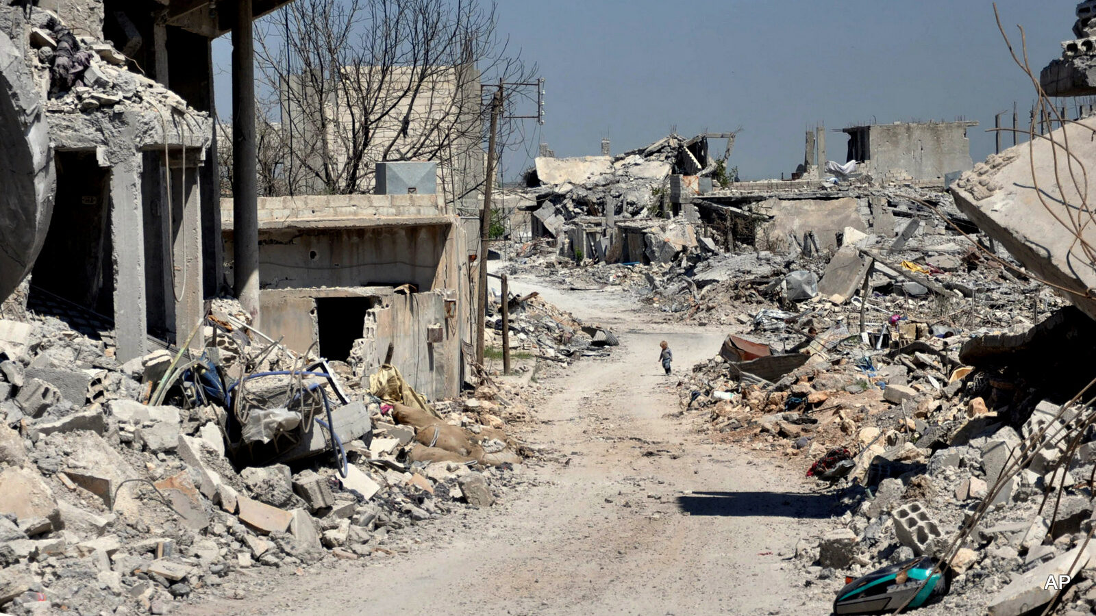A Kurdish boy, center background, walks between buildings that were destroyed during the battle between the U.S. backed Kurdish forces and the Islamic State fighters, in Kobani, north Syria. The Kurdish town on the Turkish-Syrian border is still a haunting, apocalyptic vista of hollowed out facades and streets littered with unexploded ordnance - a testimony to the massive price that came with the victory over IS. (AP Photo/Mehmet Shakir)