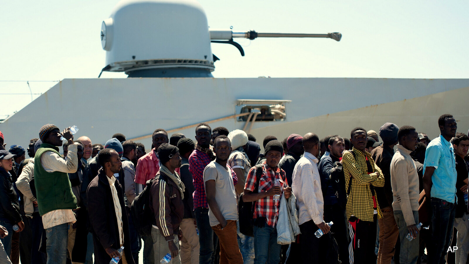 Rescued migrants line up after disembarking from the Italian Navy vessel "Bettica" in the harbor of Augusta, Sicily, southern Italy, Wednesday, April 22, 2015. Italy pressed the European Union on Wednesday to devise concrete, robust steps to stop the deadly tide of migrants on smugglers' boats in the Mediterranean, including setting up refugee camps in countries bordering Libya. Italian Defense Minister Roberta Pinotti also said human traffickers must be targeted with military intervention.