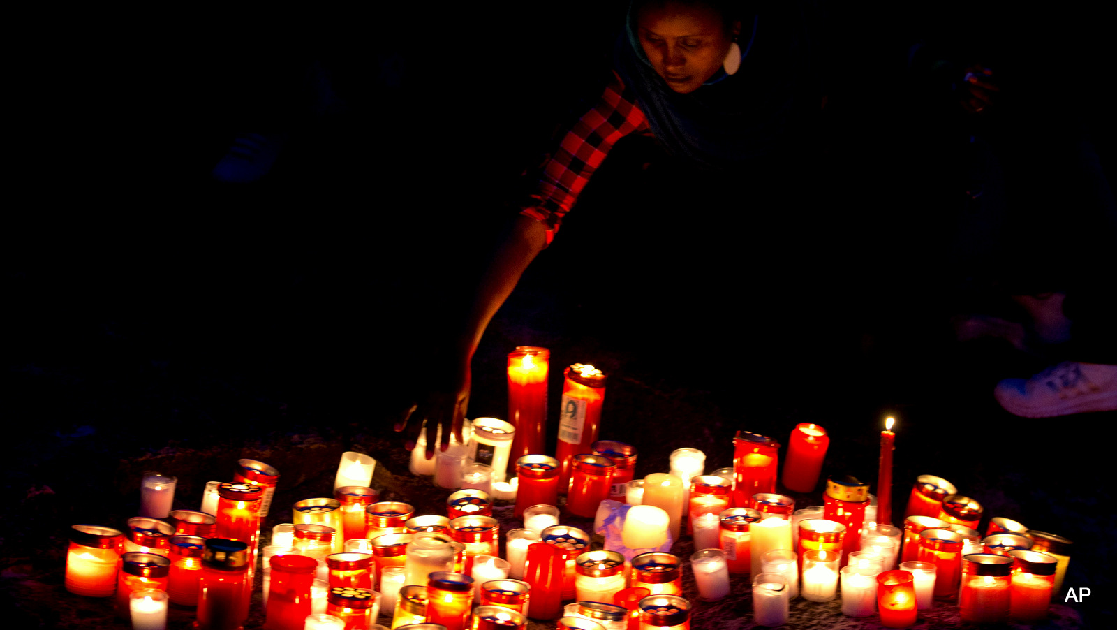 A woman lays a candle  by the sea during a candle light vigil in Sliema, in the outskirts of Valletta, Malta, Wednesday, April 22, 2015. A smuggler's boat crammed with hundreds of people overturned off the coast of Libya on Saturday as rescuers approached, causing what could be the Mediterranean's deadliest known migrant tragedy. The burial ceremony of the 24 rescued bodies will take place in Malta Thursday. 