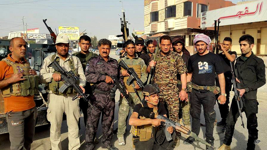 Iraqi security forces and Sunni tribal fighters pose for a photograph in central Ramadi, 70 miles (115 kilometers) west of Baghdad, Iraq, Thursday, April 16, 2015. Clashes between Iraqi forces and Islamic State militants pressing their offensive for Ramadi, the capital of western Anbar province, has forced more than 2,000 families to flee from their homes in the area, an Iraqi official said Thursday. The Sunni militants' push on Ramadi, launched Wednesday when the Islamic State group captured three villages on the city's eastern outskirts, has become the most significant threat so far to the provincial capital of Anbar.