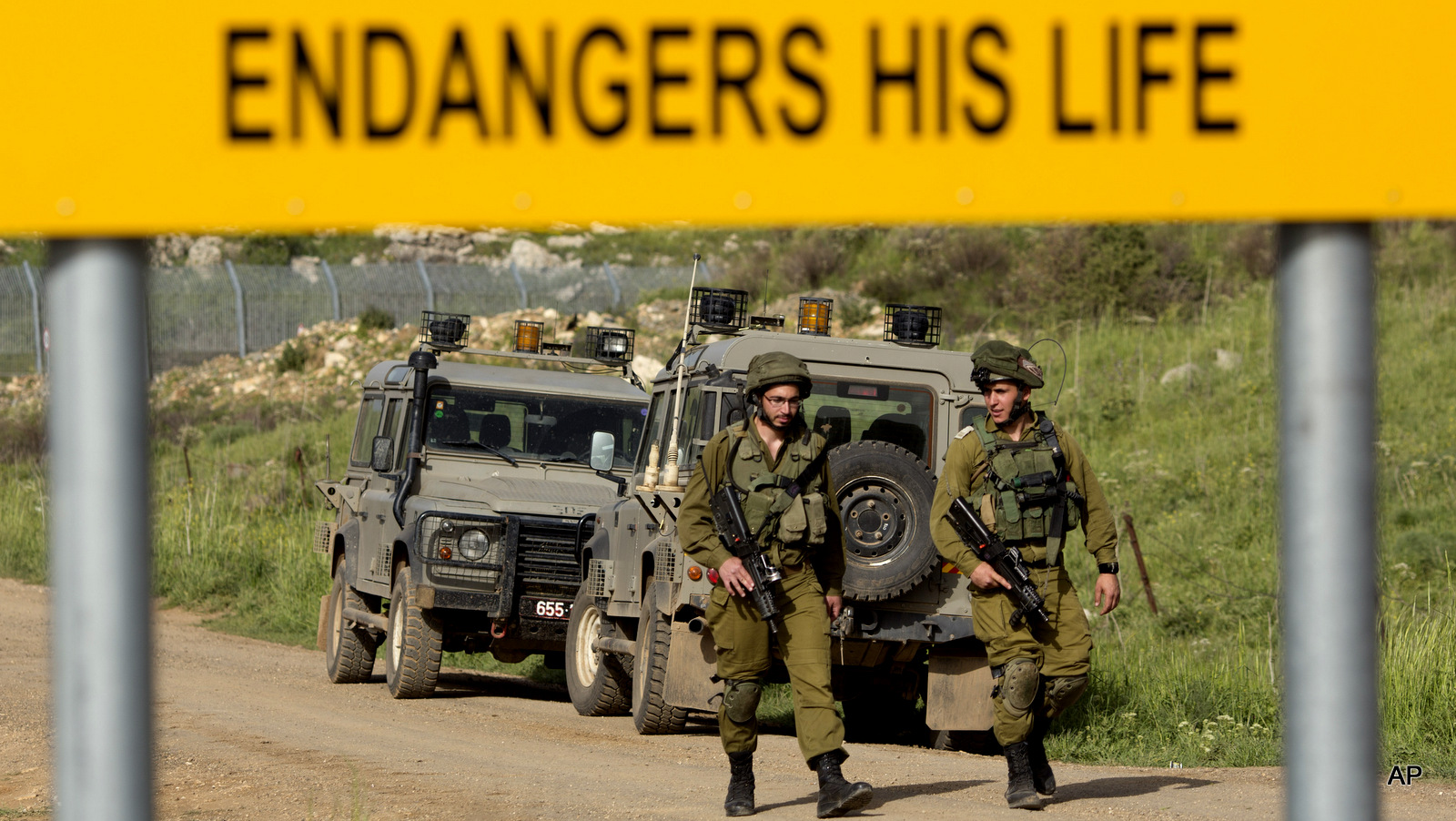 Israeli soldiers walks near the border with Syria near the site of a Sunday Israeli airstrike, in the Israeli controlled Golan Heights, Monday, April 27, 2015
