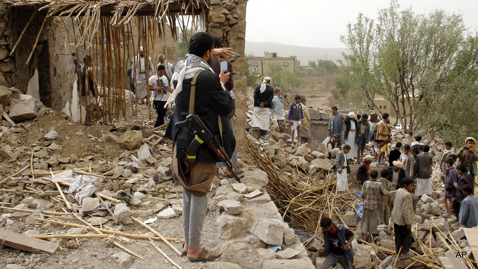 A Yemeni man uses his mobile to take photos of the rubble of houses destroyed by Saudi airstrikes in a village near Sanaa, Yemen, Saturday, April 4, 2015.
