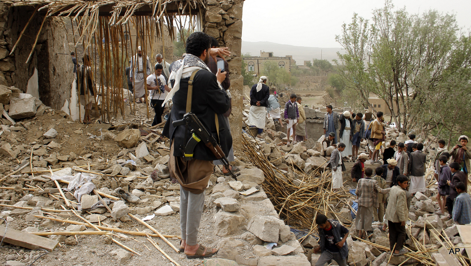 A Yemeni man uses his mobile to take photos of the rubble of houses destroyed by Saudi airstrikes in a village near Sanaa, Yemen, Saturday, April 4, 2015.