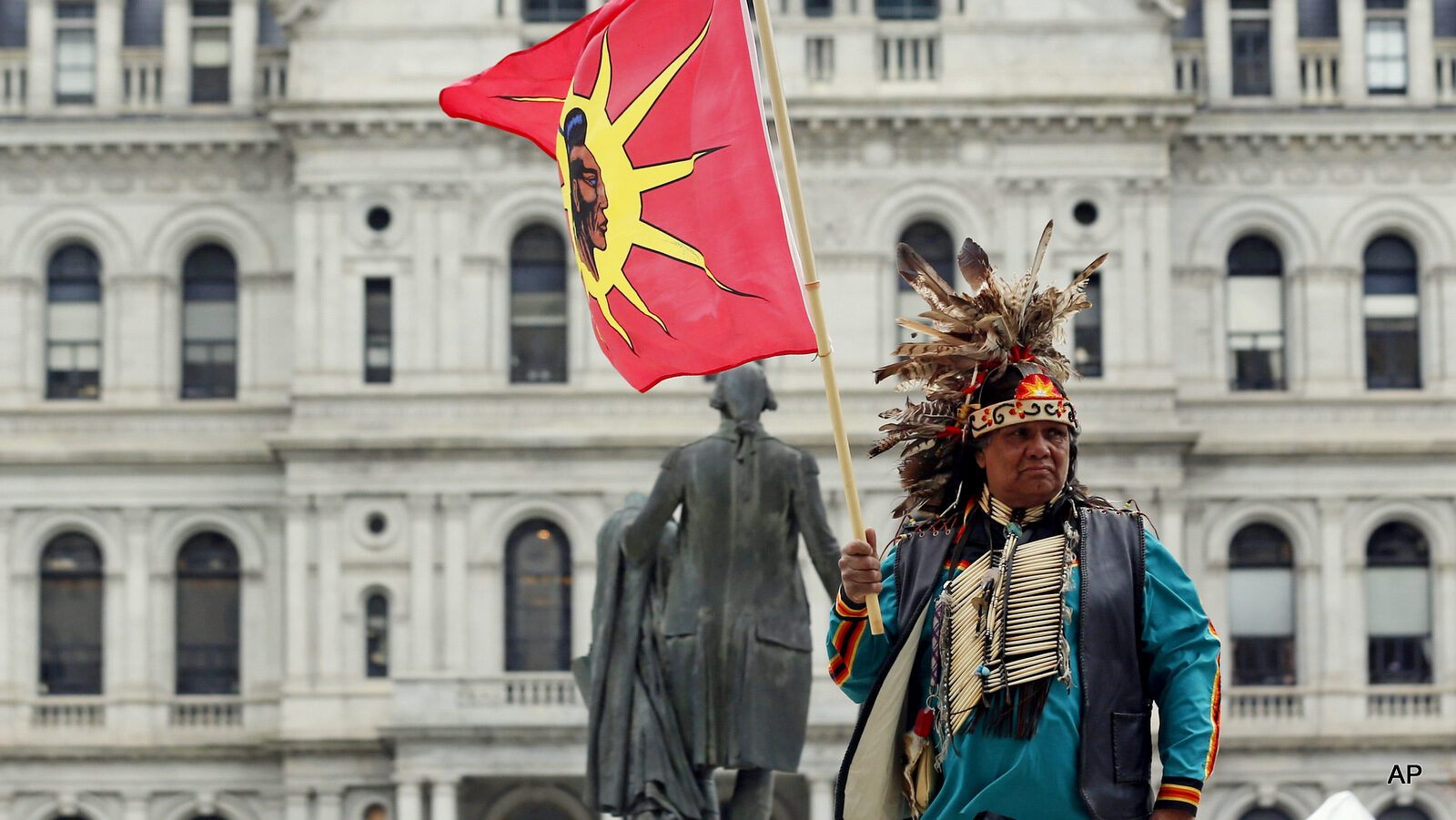Thomas Square from the Akwesasne territory in northern New York holds a flag during an Earth Day rally outside the Capitol on Wednesday, April 22, 2015, in Albany, N.Y.