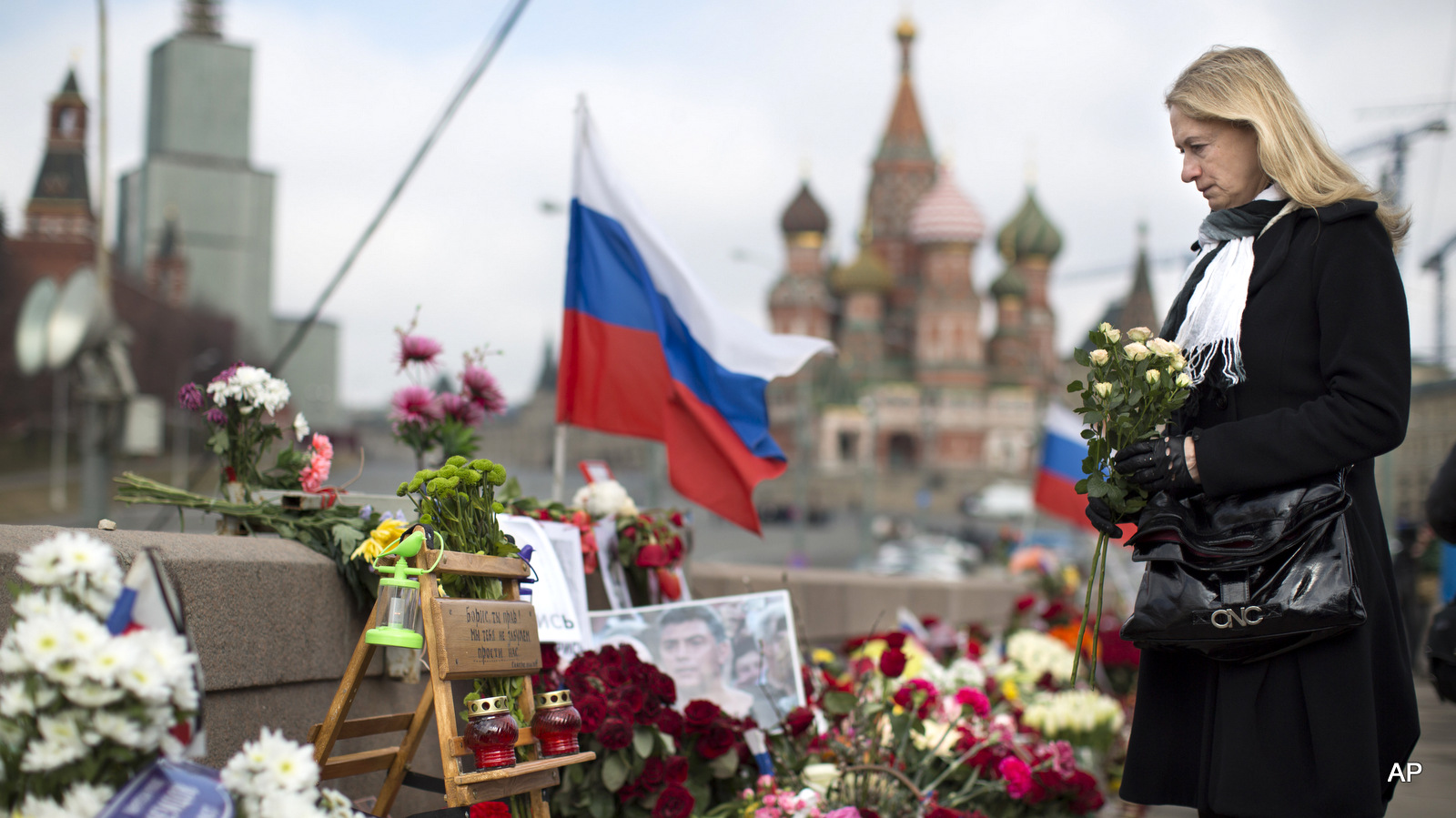 A woman lays a flower tribute at a place where Boris Nemtsov, a charismatic Russian opposition leader and sharp critic of President Vladimir Putin, was gunned down on Feb. 27, 2015 near the Kremlin in Moscow, Russia, Tuesday, April 7, 2015. Supporters of Russian opposition politician Boris Nemtsov gathered at a Moscow bridge where he was gunned down Feb. 27 to commemorate 40 days since his death, a special day in the Orthodox Christian tradition.