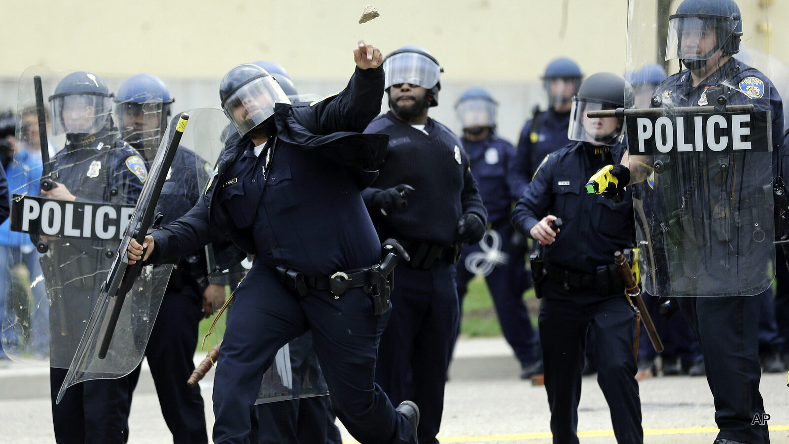 A police officer throws an object at protestors, Monday, April 27, 2015, following the funeral of Freddie Gray in Baltimore. Gray died from spinal injuries about a week after he was arrested and transported in a Baltimore Police Department van.