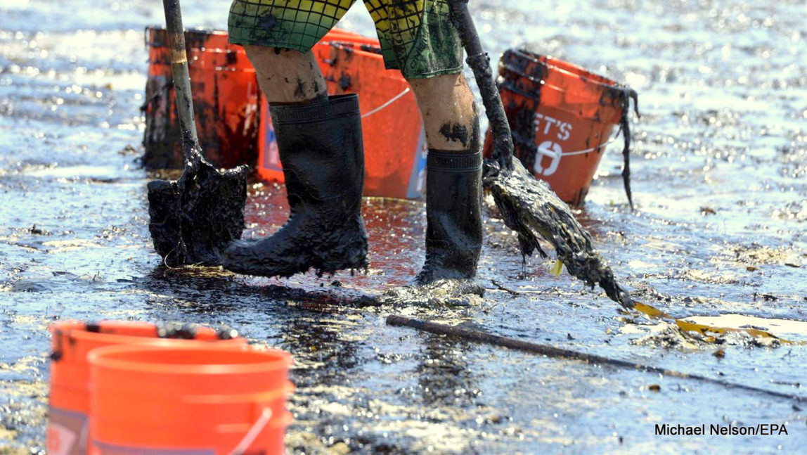 The oil sludge coated boots and shovels of a volunteer worker are seen as he cleans up an oil contaminated beach.