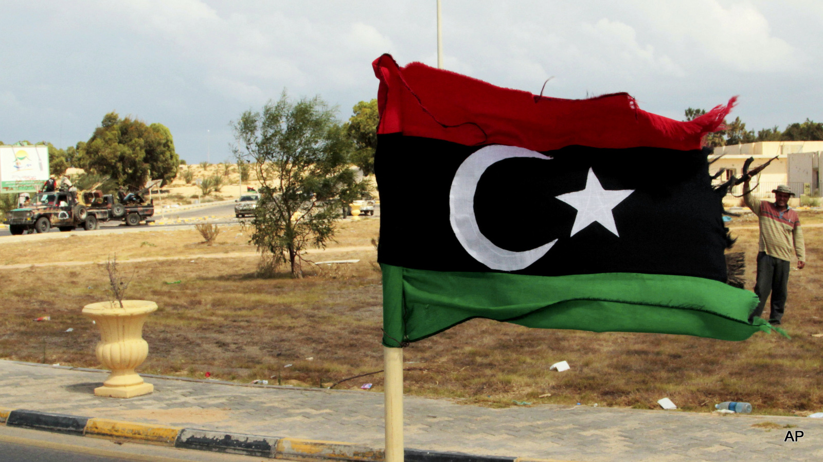 A revolutionary forces commander, Wajdi Badri, right, stands next to a pre-Gadhafi flag as he celebrates the new take over of the western main square in Sirte, Libya, Thursday, Sept. 22, 2011.  The general commanding NATO's mission in Libya said at the time that isolated groups of forces loyal to ousted strongman Moammar Gadhafi continud to be a threat to local people would be unable to coordinate their actions.