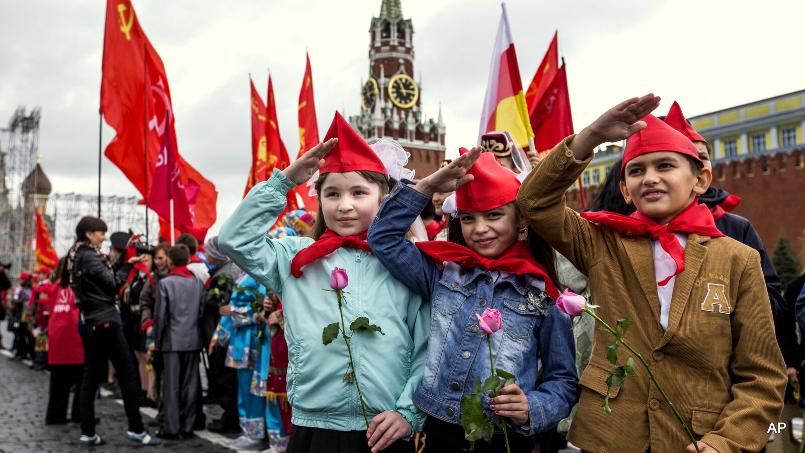 Girls and boys stand holding red neckerchiefs salute on Red Square, in front of the Spasslaya Tower, during a ceremony to celebrate joining the Pioneers organization, in Moscow, Russia, Sunday, May 17, 2015. Pro-Communist Russians try to preserve the Young Pioneers, which used to be the Communist league for pre-teens in the Soviet Union.