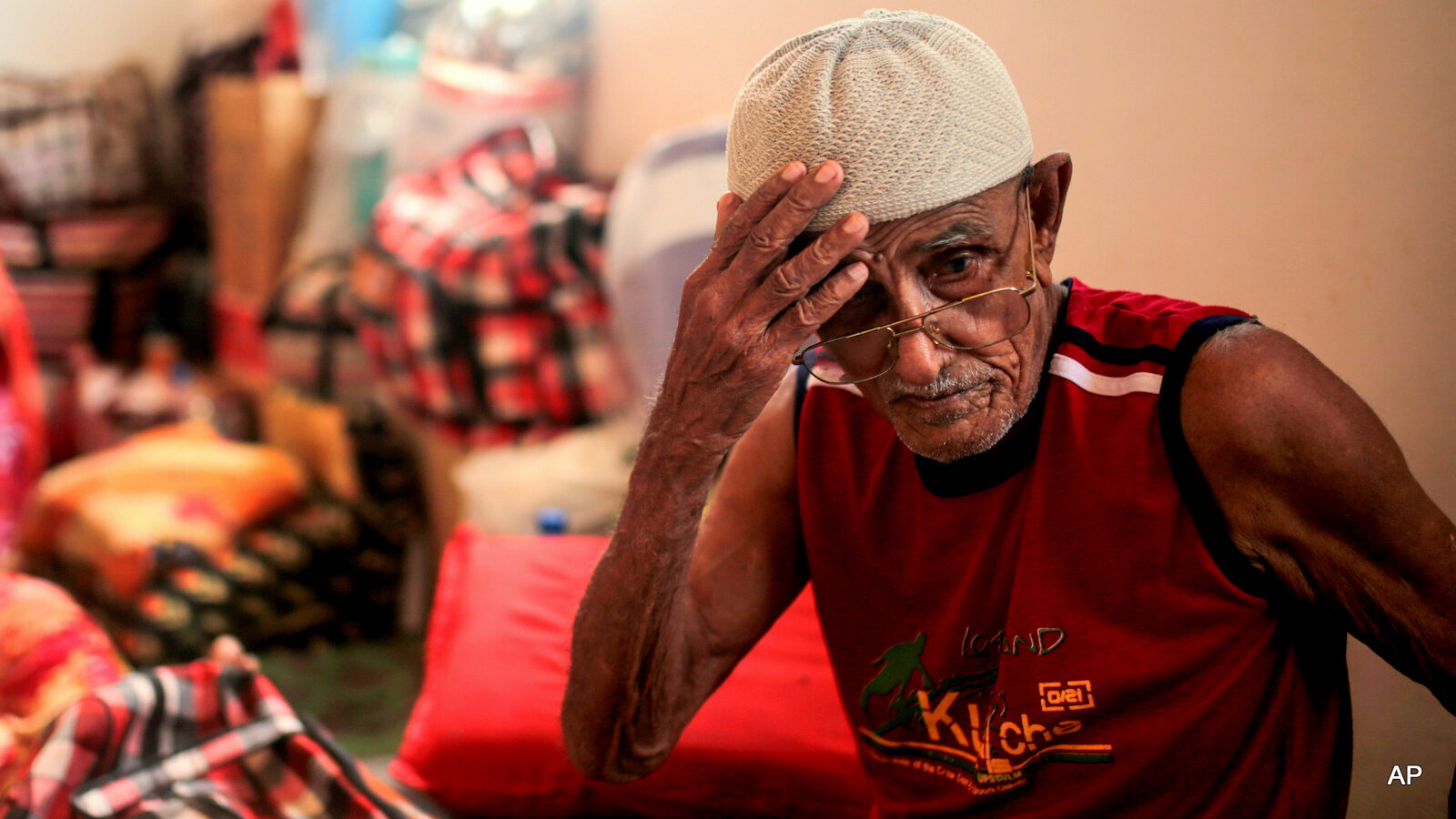 In this Tuesday, May 19, 2015 photo, Ibrahim Mohamed, 80, and the oldest refugee at the center, who is both blind and deaf, adjusts his hat, at an orphanage that has been turned into a center for Yemeni refugees, in Obock, northern Djibouti. Fleeing the war at home, thousands of Yemenis have made it across the Gulf of Aden to find refuge in Djibouti, a sleepy Horn of Africa nation where the United Nations has set up a staging hub for aid for the conflict-torn Arab country.