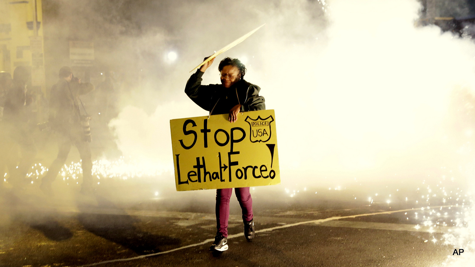 A woman runs for safety as police throw tear gas canisters