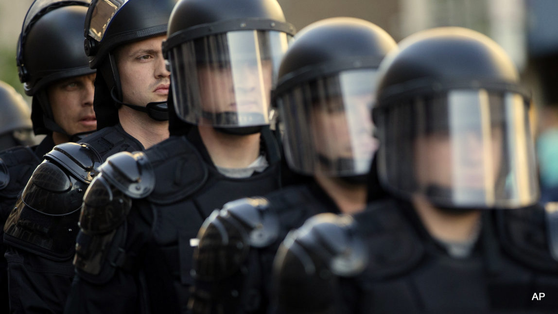 Riot police stand in formation as a protest forms against the acquittal of Michael Brelo, a patrolman charged in the shooting deaths of two unarmed suspects in Cleveland. The city of Cleveland has reached a settlement with the U.S. Justice Department over a pattern of excessive force and civil rights violations by its police department, and the agreement could be announced as soon as Tuesday, May 26, 2015, a senior federal law enforcement official said.