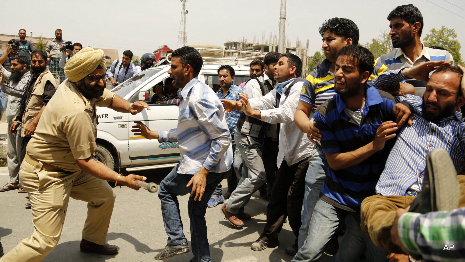 An Indian policeman beats Kashmiri government employees during a protest in Srinagar, Indian controlled Kashmir, Thursday, May 7, 2015. Indian police used teargas and force to stop government employees during a protest called by the workers’ Union demanding regularisation of contractual jobs and a hike in salary.