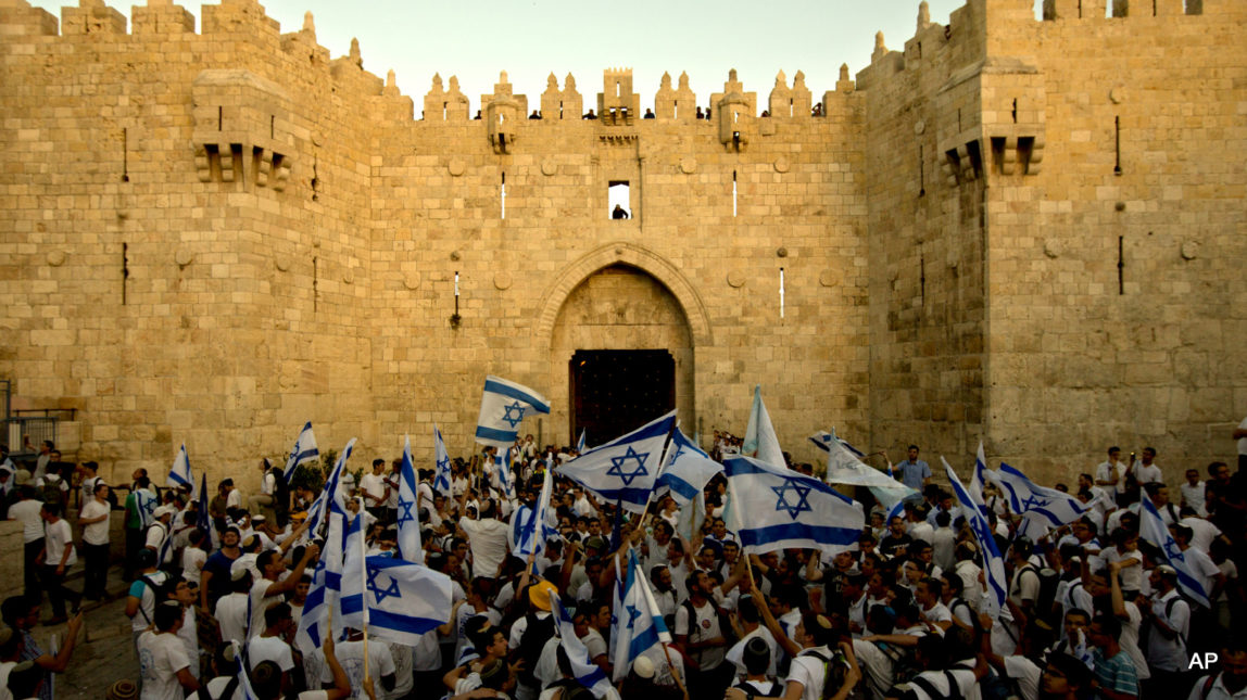 Israeli youths wave national flags as they enter Jerusalem's Old City through Damascus Gate during a march celebrating Jerusalem Day, Sunday, May 17, 2015. Under heavy police guard, thousands of Israeli demonstrators on Sunday marched through Arab sections of Jerusalem's Old City to celebrate Israel's occupation of the Palestinian land.