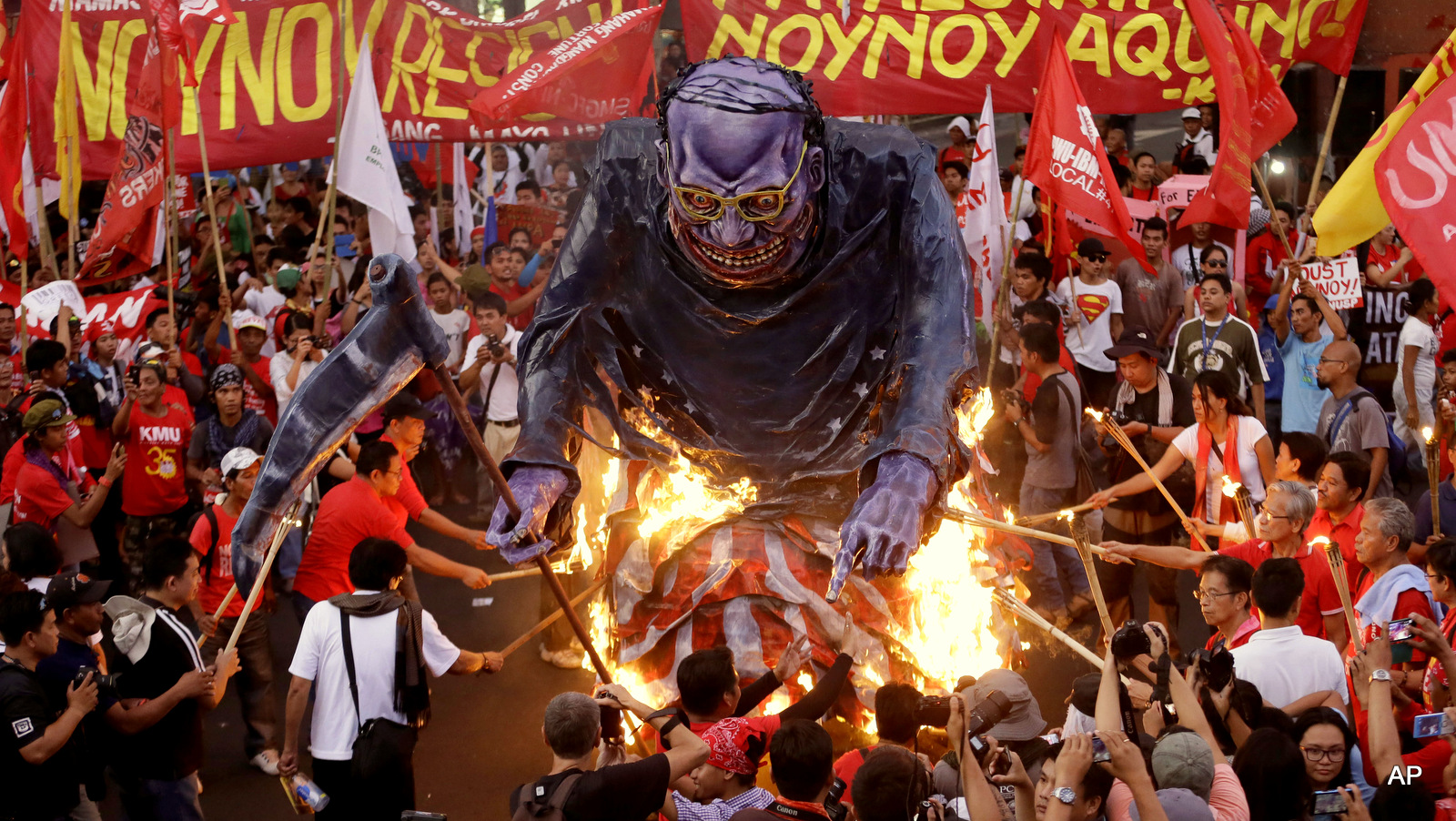 Protesters, mostly workers, set on fire to an effigy of Philippine President Benigno Aquino III during a rally near the Presidential Palace in Manila to mark May Day Friday, May 1, 2015, a national holiday in the Philippines. Thousands of workers converged near the palace to call for the resignation of Aquino, demand higher wages, better working conditions, fair export labor policies and a halt to contractualization. The sign reads: Oust Noynoy Aquino! 