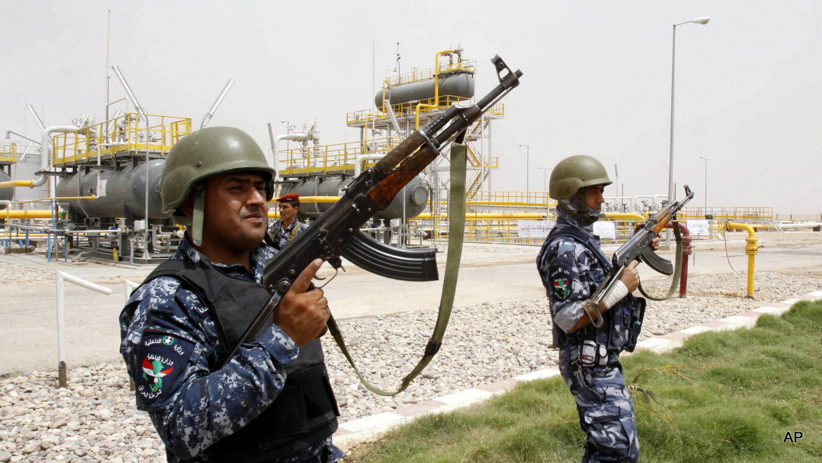 Iraqi policemen stand guard at at a newly inaugurated gas processing facility at Tuba oil field in the southern oil-rich province of Basra, 550 kilometers (340 miles) southeast of Baghdad, Iraq, Saturday, June 4, 2011. 