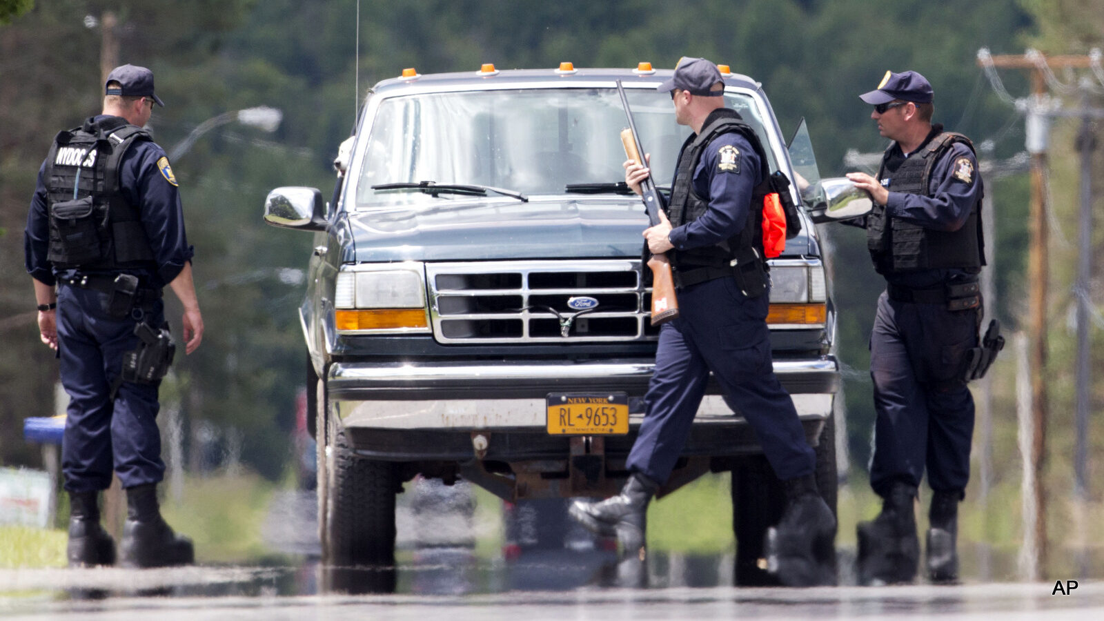 Corrections officers stop a vehicle as the search for two escaped prisoners from Clinton Correctional Facility
