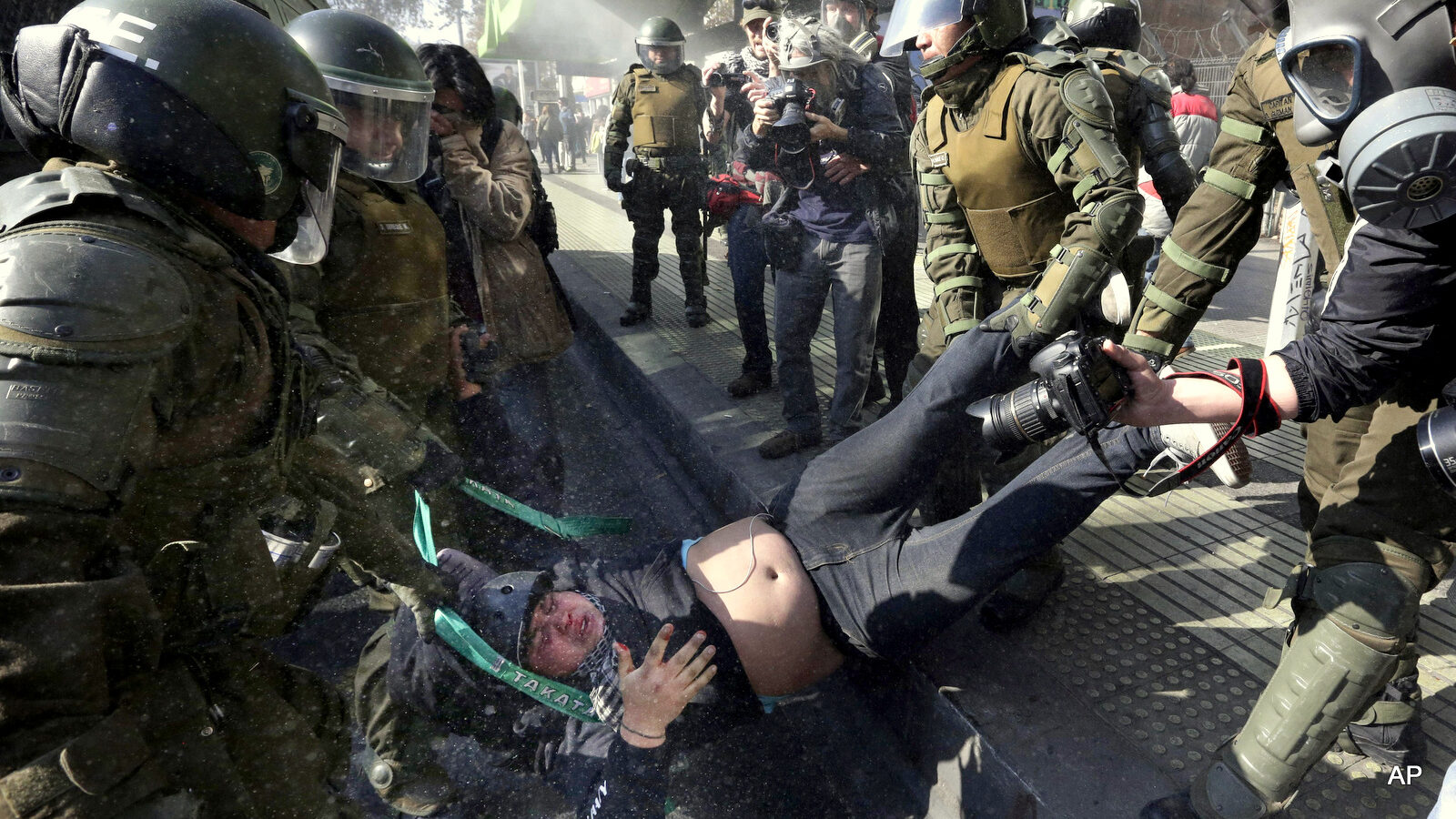 A protester is detained by riot police at the end of a march in Santiago, Chile