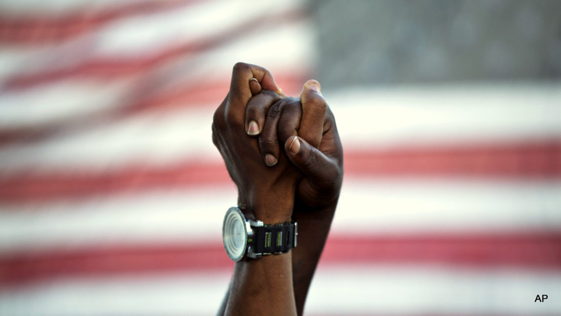 People join hands against the backdrop of an American flag