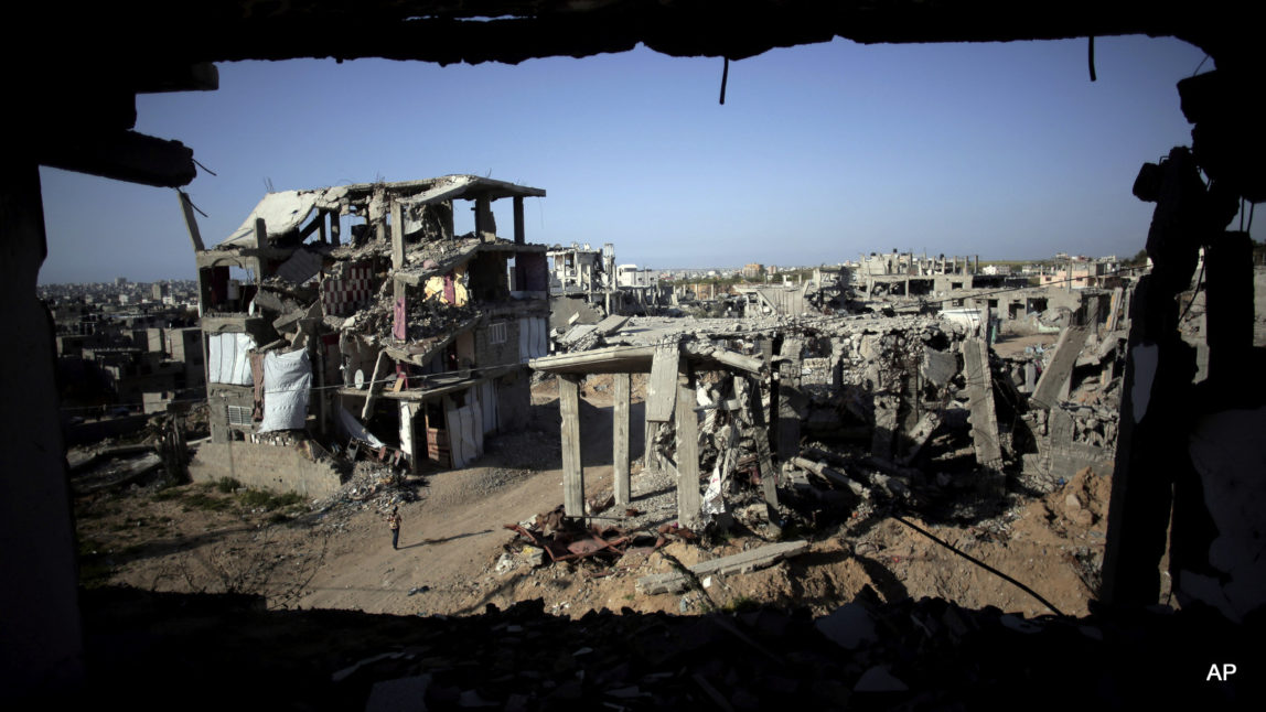 a Palestinian girl walks next to destroyed houses, in the Shijaiyah neighborhood of Gaza City