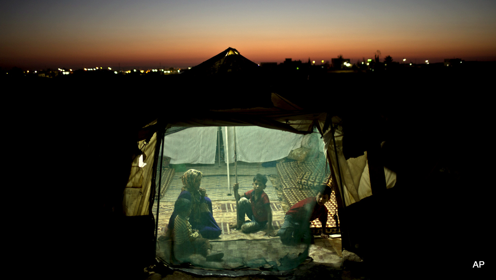 Syrian refugee Eidah Hassoun, 36, sits with her children inside their tent at an informal tented settlement near the Syrian border on the outskirts of Mafraq, Jordan.