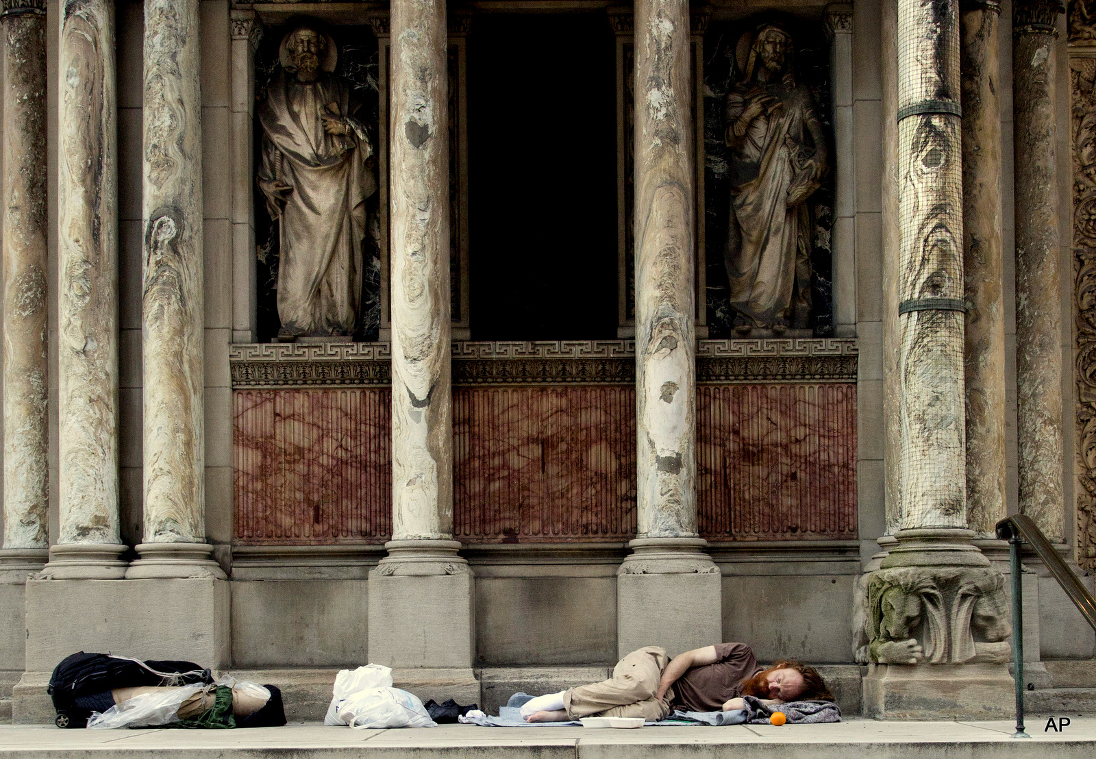 A Homeless man sleeps on the steps of St. Bartholomew's Church