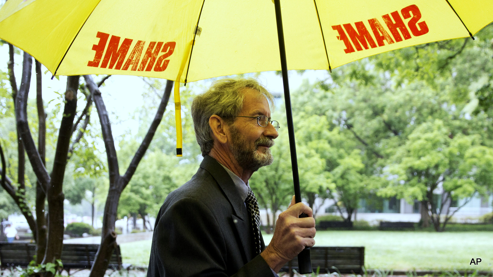Carrying an umbrella that says "shame" on it, Douglas Hughes of Florida arrives at federal court in Washington